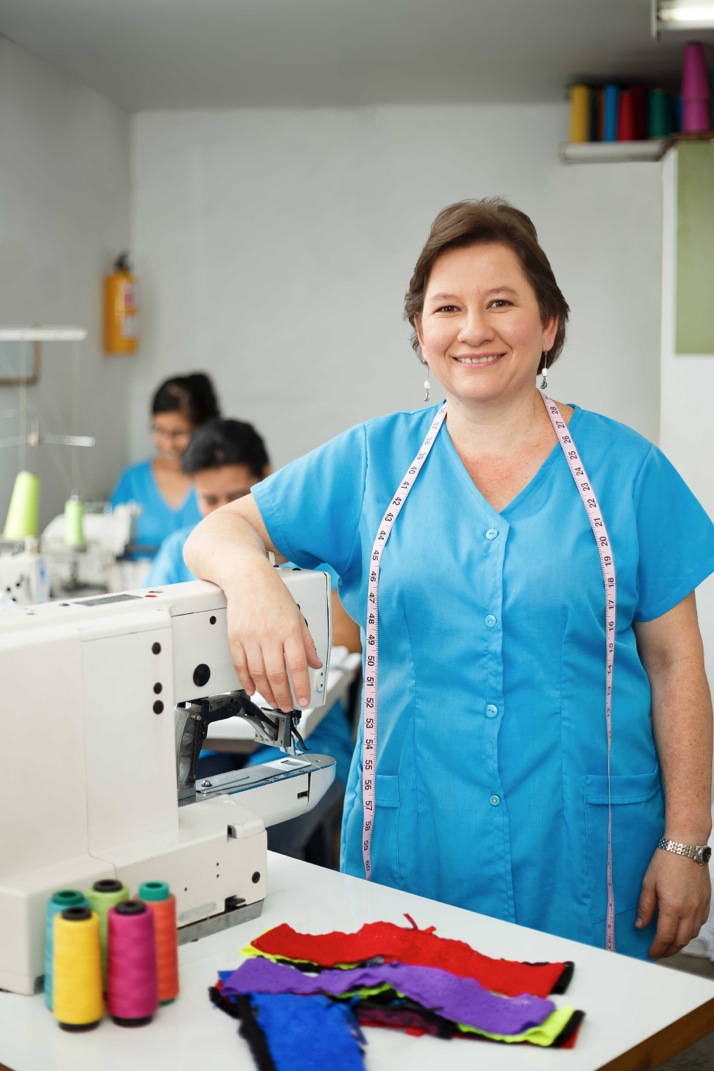 Mujer feliz frente a una maquina de coser